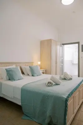 a bedroom with two beds with blue pillows at Lindos Harmony Suites in Líndos