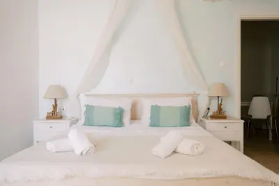 a bedroom with a white bed with two night stands at Lindos Harmony Suites in Líndos