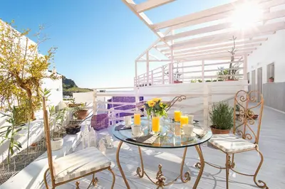 a patio with a glass table and chairs on a balcony at Lindos Harmony Suites in Líndos