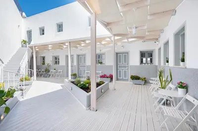 an outdoor patio with white furniture and plants at Lindos Harmony Suites in Líndos