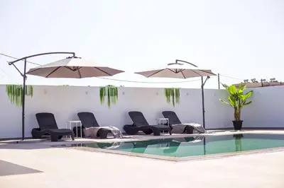 a pool with chairs and tables and umbrellas at Platanos House in Faliraki