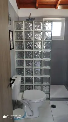 a bathroom with a toilet and a wall of glass shelves at Platanos House in Faliraki