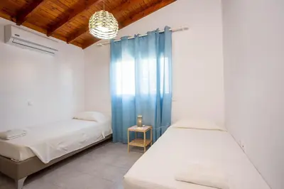a bedroom with two beds and a blue curtain at Platanos House in Faliraki
