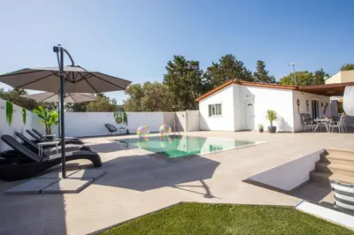 a patio with a pool and an umbrella and chairs at Platanos House in Faliraki