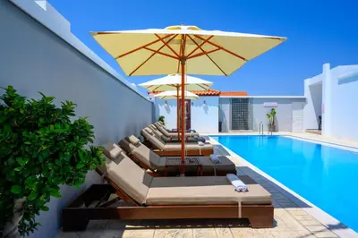 a swimming pool with lounge chairs and an umbrella at Pervolia House Private Villa Near Airport in Kremasti
