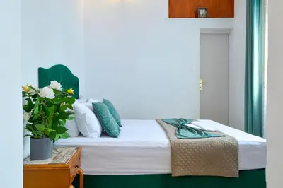 a bedroom with a bed with green and white pillows at mascot traditional guest house in Rhodes Town