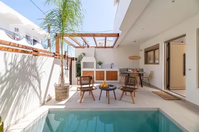 an outdoor patio with a swimming pool and a table and chairs at Mariann Premium Suites in Lardos