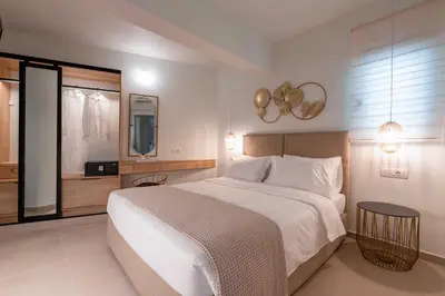 a bedroom with a large white bed and a bathroom at Mariann Premium Suites in Lardos