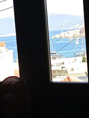 a window with a view of the ocean and a boat at Casa Con Vista Apartments in Halki