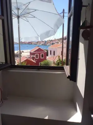 a window with a view of a beach and the ocean at Casa Con Vista Apartments in Halki