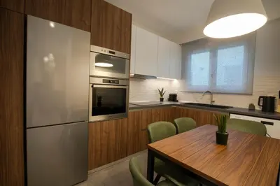 a kitchen with a wooden table and a stainless steel refrigerator at Unique Central Lee Pham Apartment in Rhodes Town