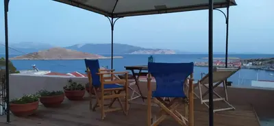 a table and chairs on a deck with a view of the water at Marina Castellana Studios II in Halki