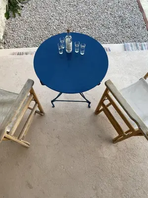 a blue table with glasses and a bottle and two chairs at Marina Castellana Studios II in Halki
