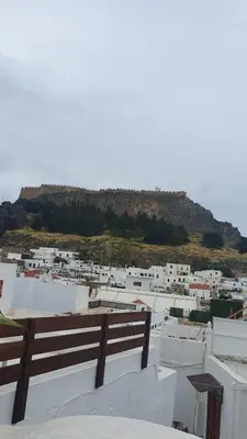 a group of white buildings with a hill in the background at Toulipa Lindos in Líndos