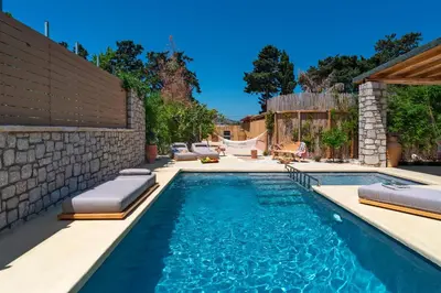 a swimming pool with two chaise lounges in a backyard at Eftopia Villa Kolympia by Onar Villas in Kolimbia