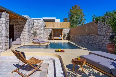 a backyard with a swimming pool with chairs and a table at Eftopia Villa Kolympia by Onar Villas in Kolimbia