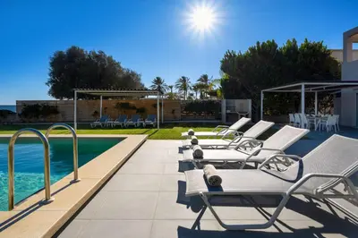 a row of lounge chairs next to a swimming pool at Sea Homes Villas-Villa Sylvia in Kiotari