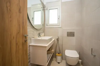 a bathroom with a sink and a toilet and a mirror at Sea Homes Villas-Villa Sylvia in Kiotari