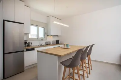 a kitchen with white cabinets and a wooden island with stools at Sea Homes Villas-Villa Sylvia in Kiotari
