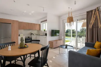 a kitchen and living room with a table and a couch at Ossiano Pool Villas,Heating Pool, 2 min drive to Haraki Beach & 10 min to Lindos in Haraki