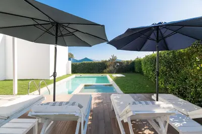 two umbrellas and two chairs and a swimming pool at Ossiano Pool Villas,Heating Pool, 2 min drive to Haraki Beach & 10 min to Lindos in Haraki