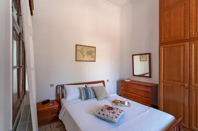 a bedroom with a white bed with a wooden dresser at Traditional 3 bedroom house in the Old Town in Rhodes Town