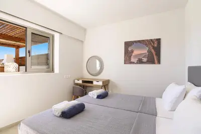 a white bedroom with a bed and a window at Villa Angelina Olivestone by Villa Plus in Yennadhion