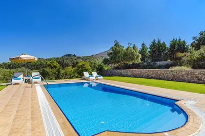 a swimming pool in a yard with chairs and an umbrella at Villa Ermis Springs by Villa Plus in Kolimbia