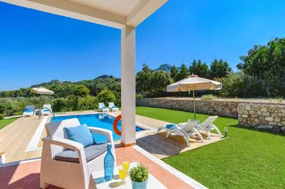 a backyard with a pool and chairs and an umbrella at Villa Ermis Springs by Villa Plus in Kolimbia