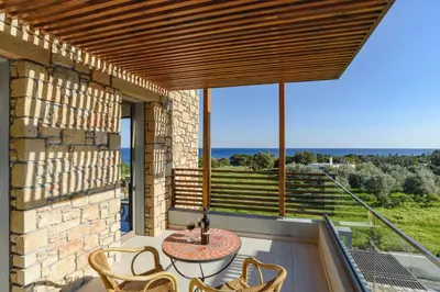 a patio with a table and chairs on a balcony at Villa Eva Olivestone by Villa Plus in Yennadhion