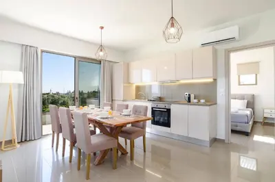 a kitchen and dining room with a table and chairs at Villa Eva Olivestone by Villa Plus in Yennadhion