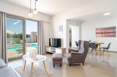 a living room with a couch and a tv and a table at Villa Eva Olivestone by Villa Plus in Yennadhion