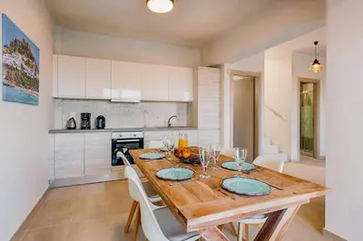 a kitchen with a wooden table and chairs in a kitchen at Villa Nikos Olivestone by Villa Plus in Yennadhion