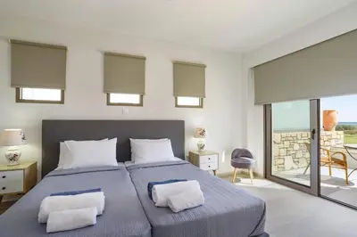 a bedroom with a large bed with two pillows at Villa Nikos Olivestone by Villa Plus in Yennadhion