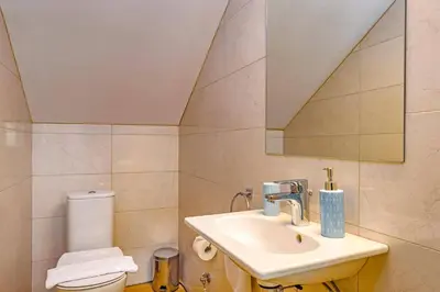 a bathroom with a sink and a toilet and a mirror at Villa Paleos Aegean by Villa Plus in Ialyssos