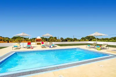 a large swimming pool with chairs and umbrellas at Villa Paleos Aegean by Villa Plus in Ialyssos