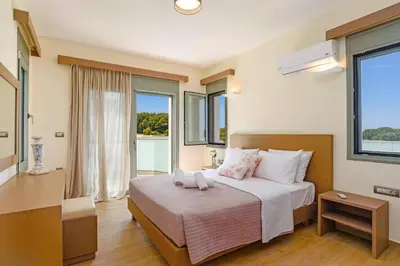 a bedroom with a bed with white sheets and windows at Villa Paleos Aegean by Villa Plus in Ialyssos