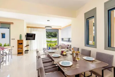 a dining room with a wooden table and chairs at Villa Paleos Aegean by Villa Plus in Ialyssos