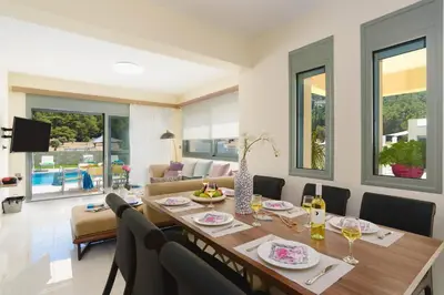 a dining room with a long table and chairs at Villa Paleos Evergreen by Villa Plus in Ialyssos