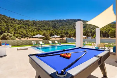 a pool table on a patio next to a swimming pool at Villa Paleos Evergreen by Villa Plus in Ialyssos
