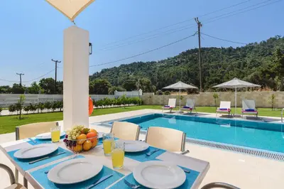 a table with a bowl of fruit on it next to a swimming pool at Villa Paleos Hillside by Villa Plus in Ialyssos