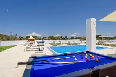 a pool table with balls on it next to a swimming pool at Villa Paleos Sunset by Villa Plus in Ialyssos