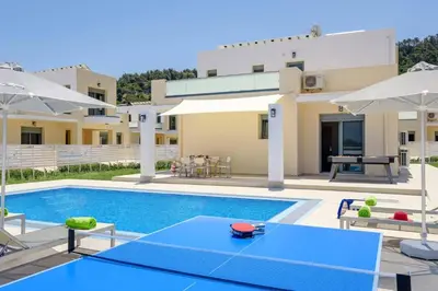 a villa with a swimming pool in front of a house at Villa Paleos Sunset by Villa Plus in Ialyssos