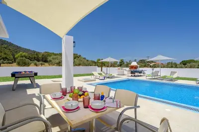 a dining table and chairs next to a swimming pool at Villa Paleos Sunset by Villa Plus in Ialyssos