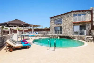 a pool with a couch and a chair next to a building at Villa Alcyone Seastone by Villa Plus in Kiotari