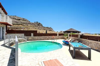 a pool with a ping pong table in a backyard at Villa Alcyone Seastone by Villa Plus in Kiotari