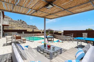 a patio with a couch and a table and a pool at Villa Alcyone Seastone by Villa Plus in Kiotari