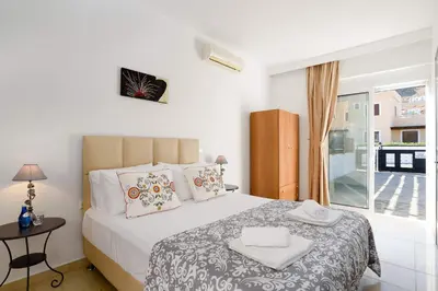 a white bedroom with a bed and a window at Villa Alexia by Villa Plus in Pefki Rhodes