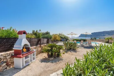 a house with a fireplace next to a pool at Villa Aqua Blu by Villa Plus in Líndos