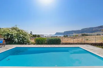 a blue swimming pool with a view of the ocean at Villa Aqua Blu by Villa Plus in Líndos